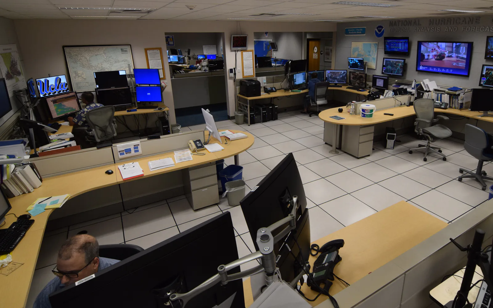 Forecasters working among maps and monitors in a hurricane operations centre
