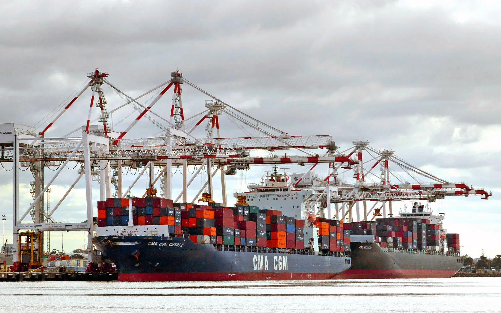 Container ships being worked beneath cranes at the Port of Melbourne